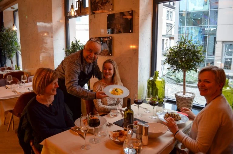 Gjester får servert pasta ved vindusbordet hos Amici Miei