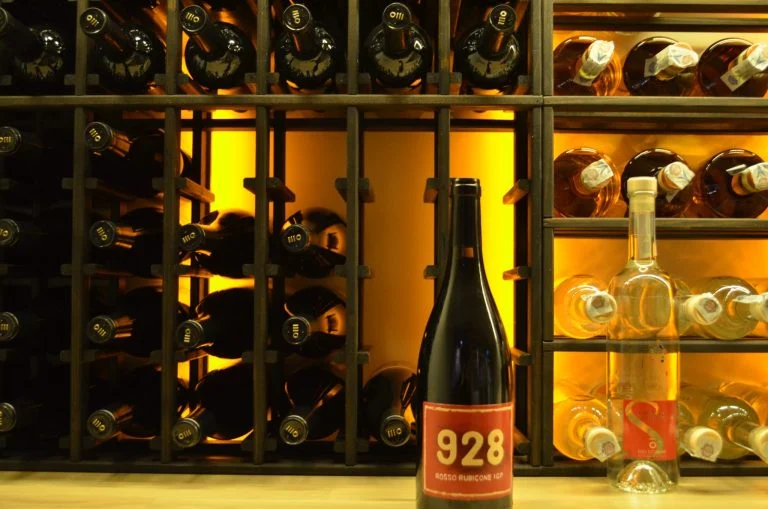 Egenimportert rødvin 928 Rosso Rubicone foran vinreolen i vinkjelleren